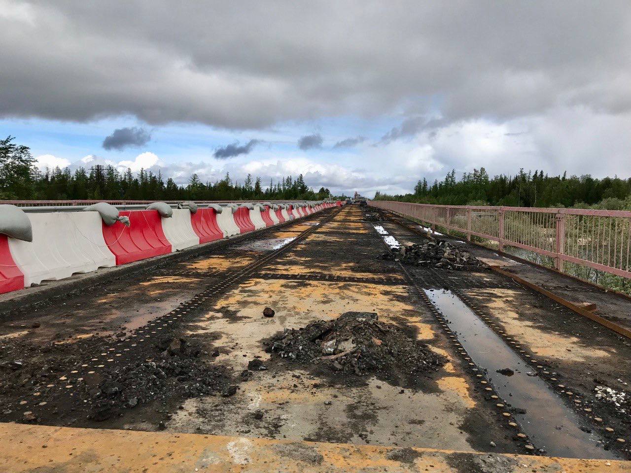 Рабочий процесс на мосту через реку ПякупурЗдесь сейчас дорожные рабочие укрепляют берегоукрепительные сооружения (конуса), п...